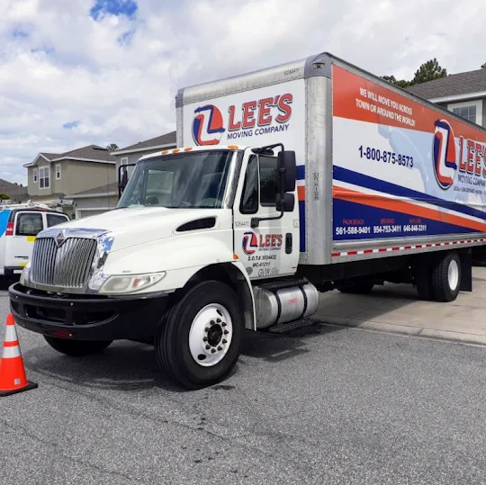 Lee's Moving Company box truck parked in the driveway of a Delray Beach single-family home on a tree-lined street, crew ready to load